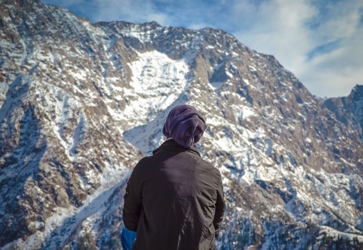 man sat looking at snowy mountain